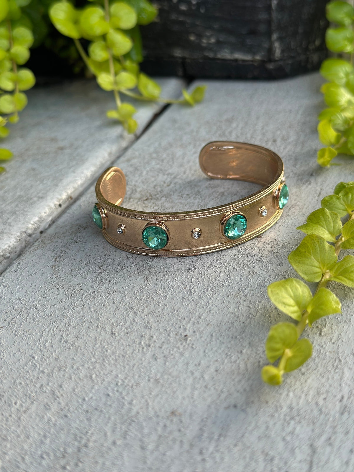 Gold cuff bracelet with green gemstones