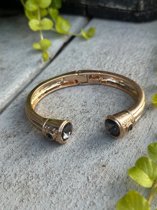 Gold cuff bangle with a dark gemstone