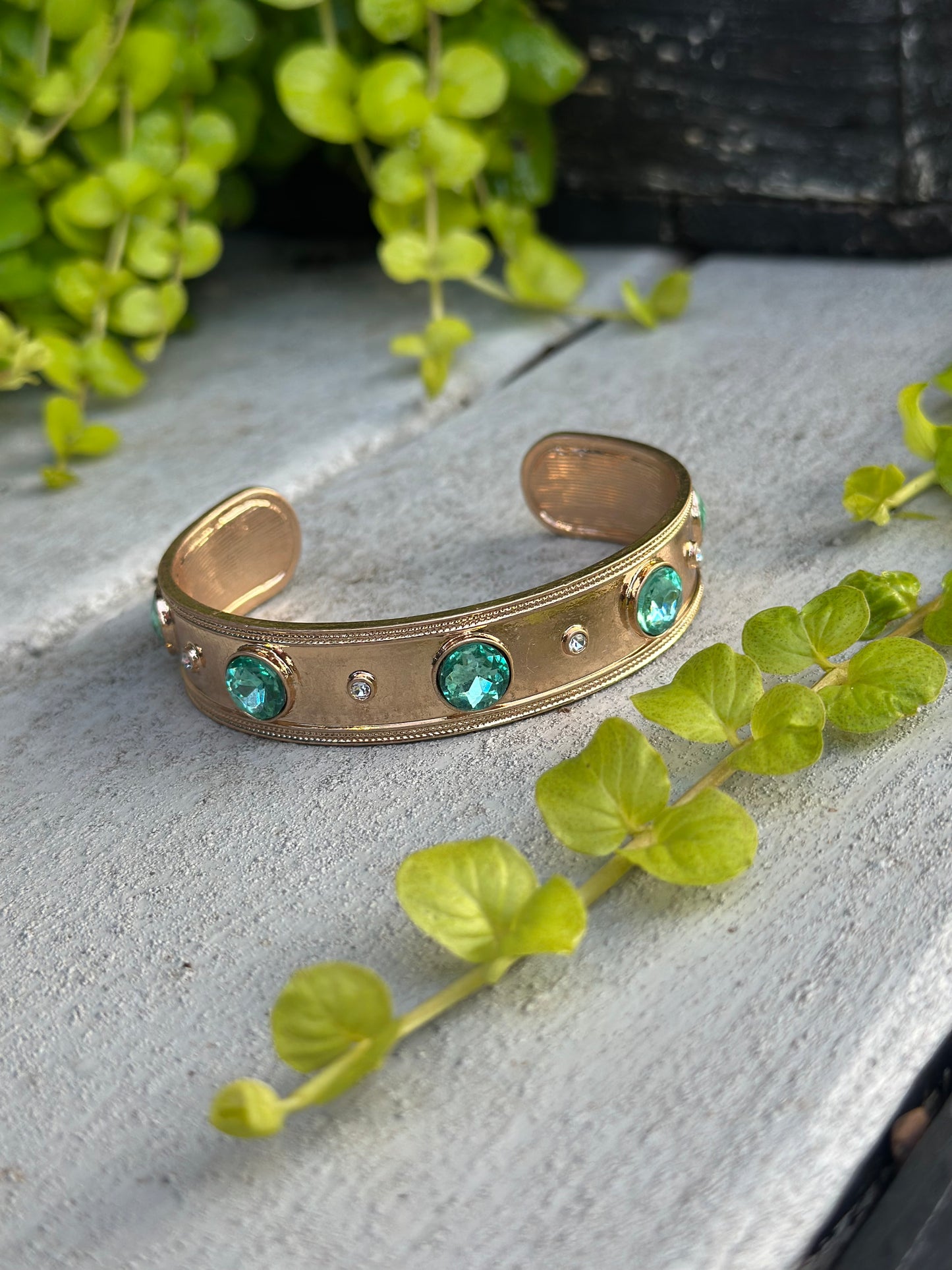 Gold cuff bracelet with green gemstones